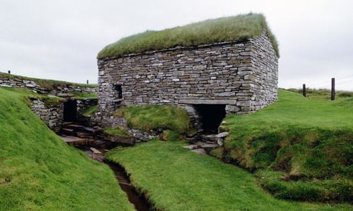 A small grass-covered house built over a small stream